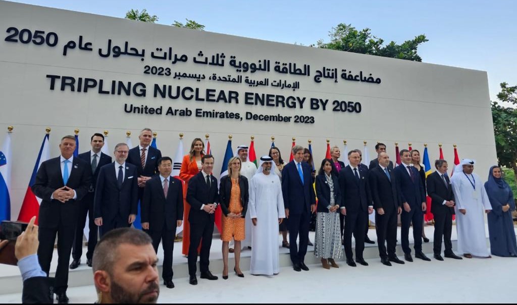 Dignitaries assembled with their flags, in front of a background which reads “Tripling Nuclear Energy by 2050, United Arab Emirates, December 2023”