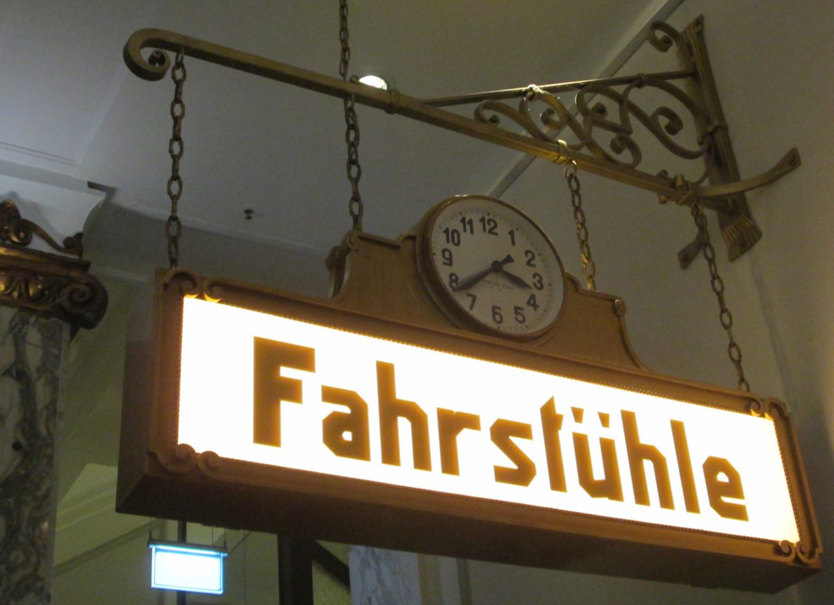 An ornate illuminated sign with the German text "Fahrstühle", also incorporating a clock